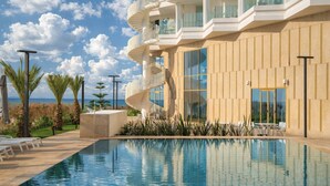 A modern hotel with a pool, a spiral staircase, and a view of the sea. - STORY Le Carrousel Rabat (Rabat)