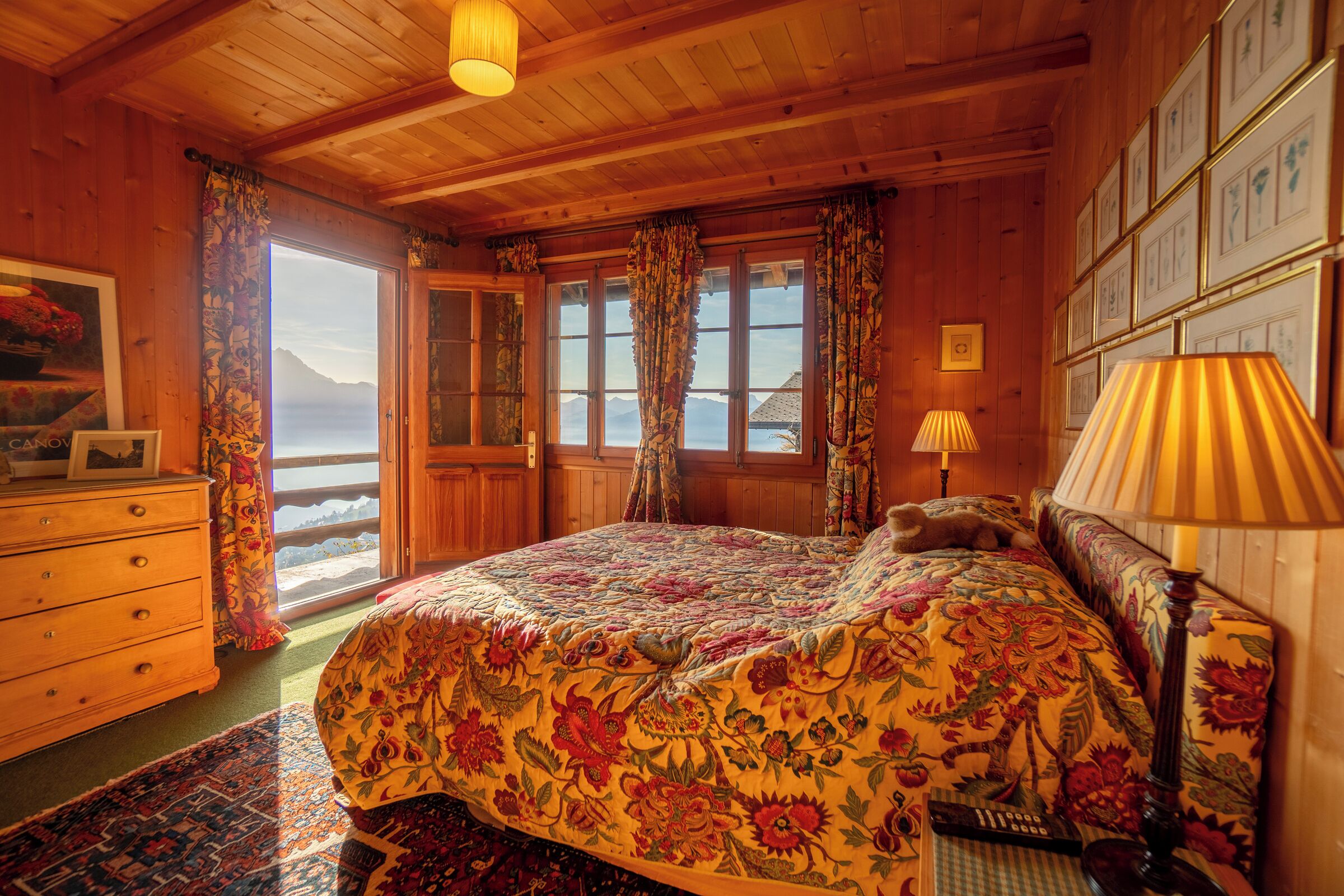 Ein Schlafzimmer einer Holzhütte mit einem großen Bett, einem Schminktisch und Blick auf die Berge.