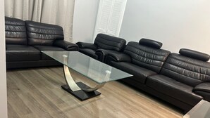 A modern living room with a glass coffee table, black leather sofa, and wooden flooring. - Edinburgh City Centre 3BR Fully Refurbished (Edinburgh)