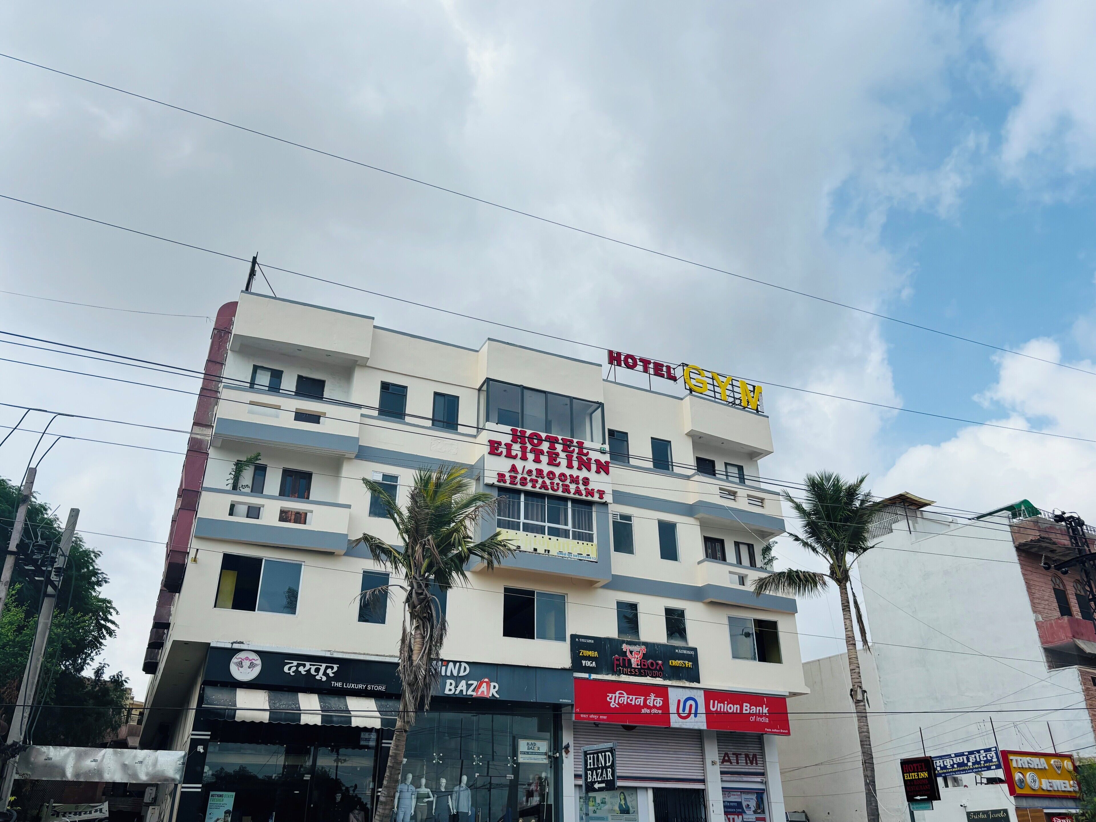 Un edificio a più piani con un hotel chiamato "Hotel Elite Inn" e una palestra all'ultimo piano.