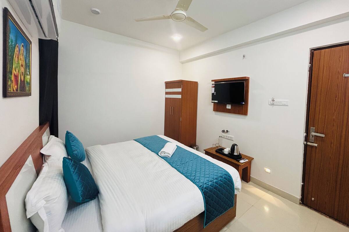 Una habitación de hotel con cama, armario, televisor y puerta.