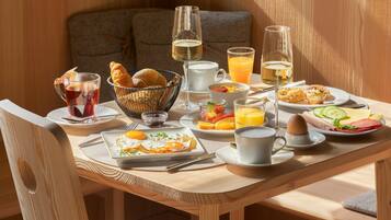 A breakfast table with croissants, eggs, fruit, and beverages.