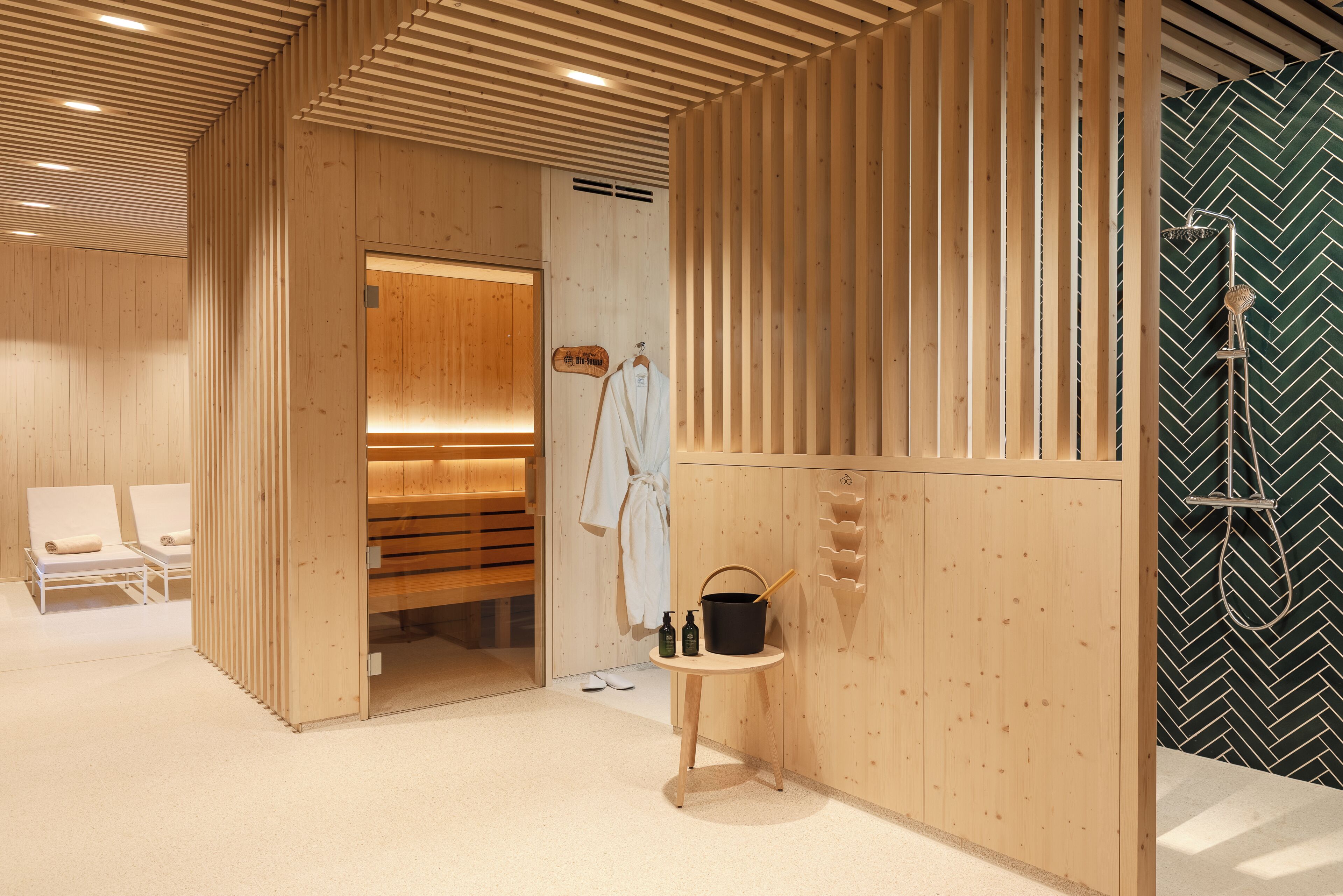 Interior de madera con mostrador de recepción, un banco y una mesita con artículos de aseo.