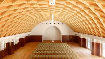 Auditorio, jossa on ainutlaatuinen, geometrisesti muotoiltu kattorakenne, useita rivissä olevia tuolirivejä ja keskeinen esiintymislava.
