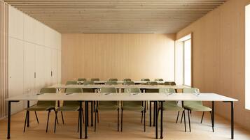 A conference room with a long table, green chairs, and a wooden ceiling.