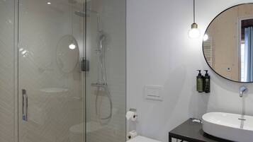 Ein modernes Badezimmer mit einer gläsernen Duschkabine, einer weißen Toilette, einem Holzwaschtisch mit Waschbecken und einem Spiegel.