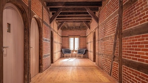 A corridor with brick walls, wooden flooring, and a window at the end. - Hotel Krone (Oettingen in Bayern)