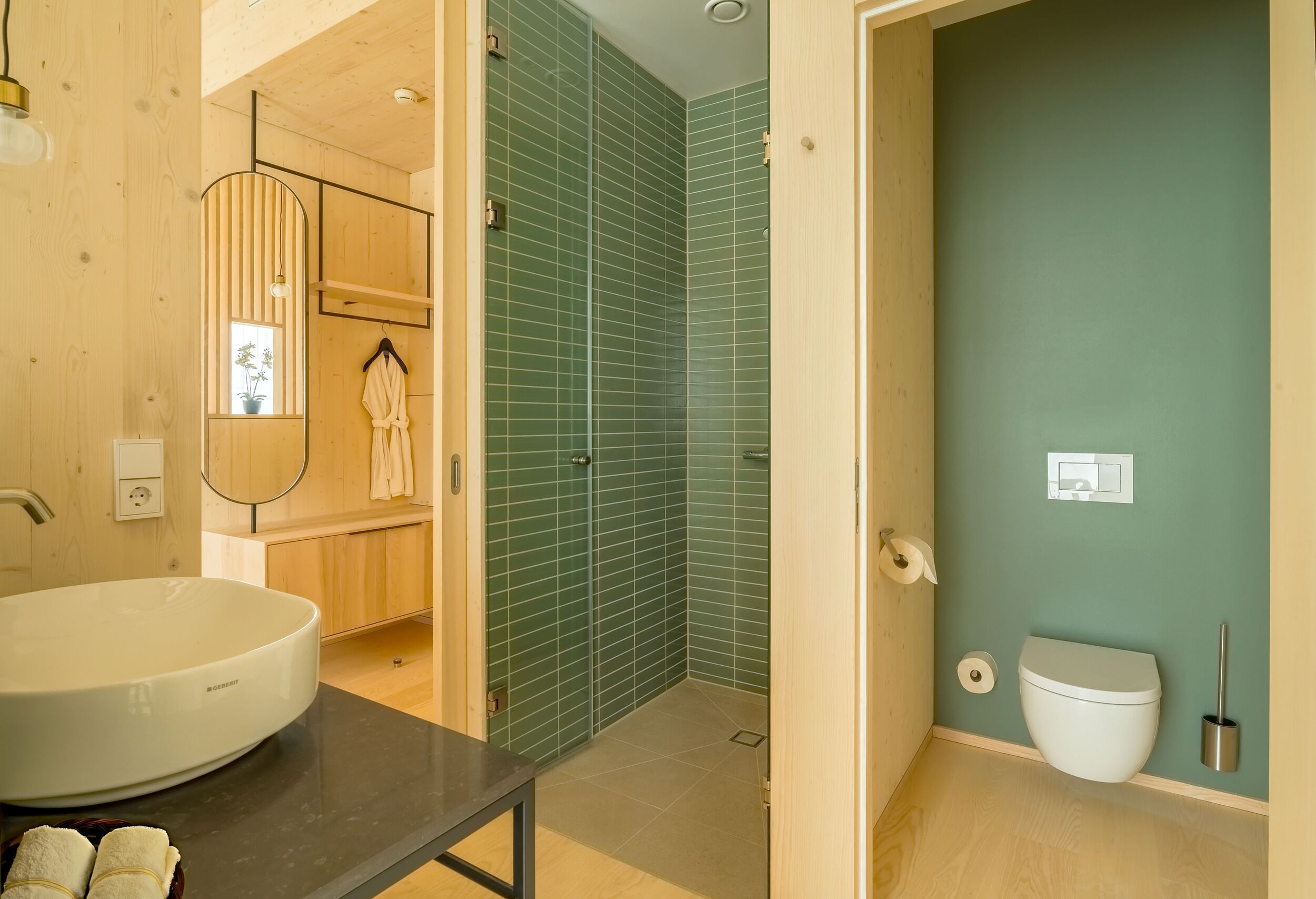 Un baño moderno con un lavabo redondo, ducha a ras de suelo y un inodoro.