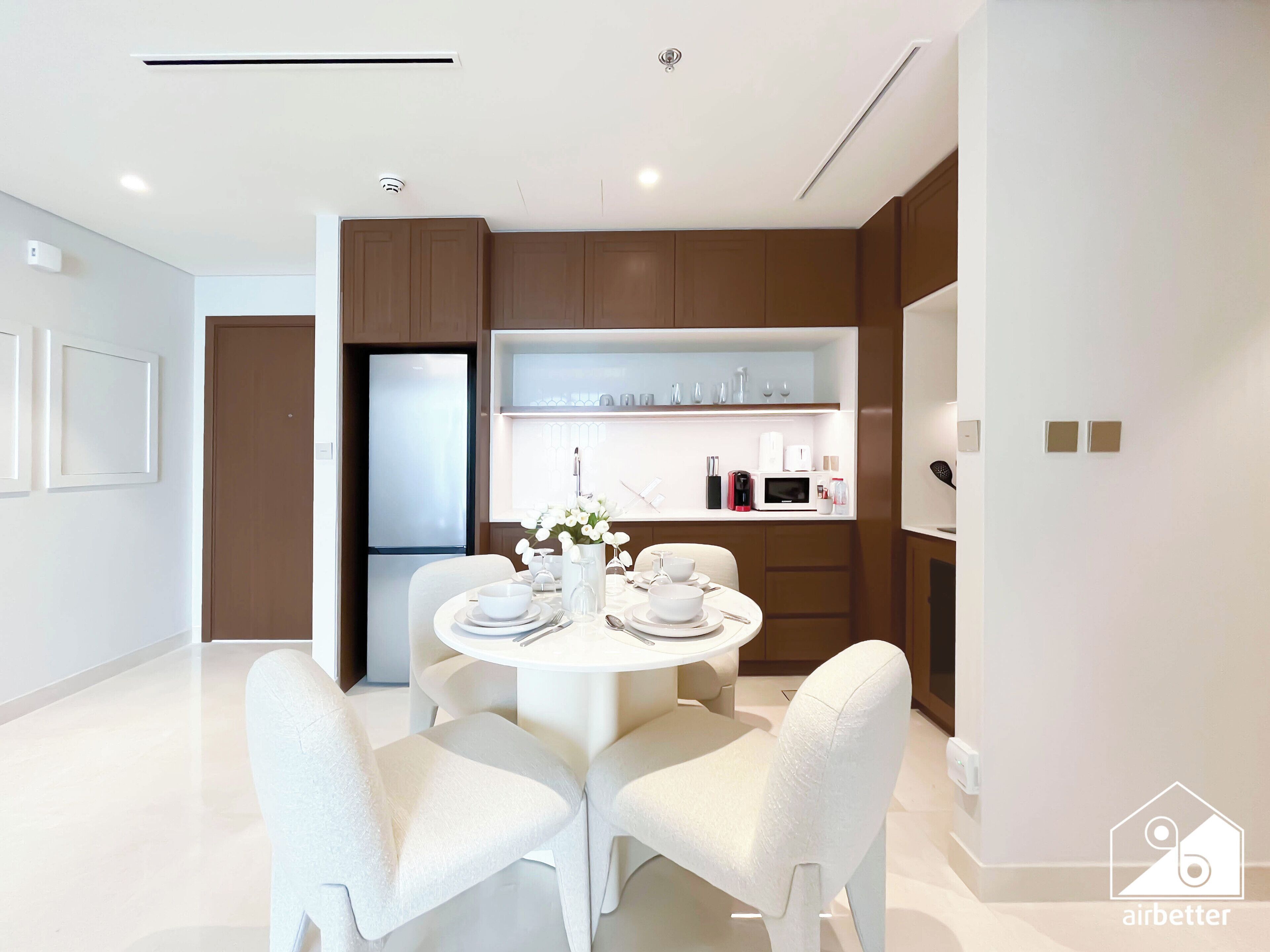 A modern kitchen with white appliances, a round dining table, and white chairs.