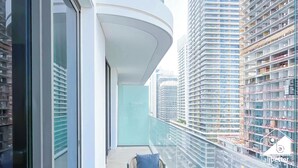 Un bâtiment moderne doté d’un balcon incurvé, de grandes fenêtres et offrant une vue sur d’autres immeubles de grande hauteur.