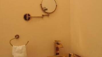 A bathroom with a gold sink, a towel rack, and a mirror.