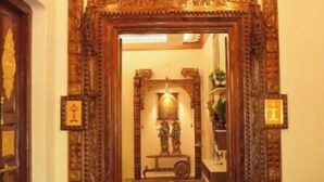 Une porte d’entrée en bois richement décorée, agrémentée d’un miroir, d’un lustre et d’un paillasson.