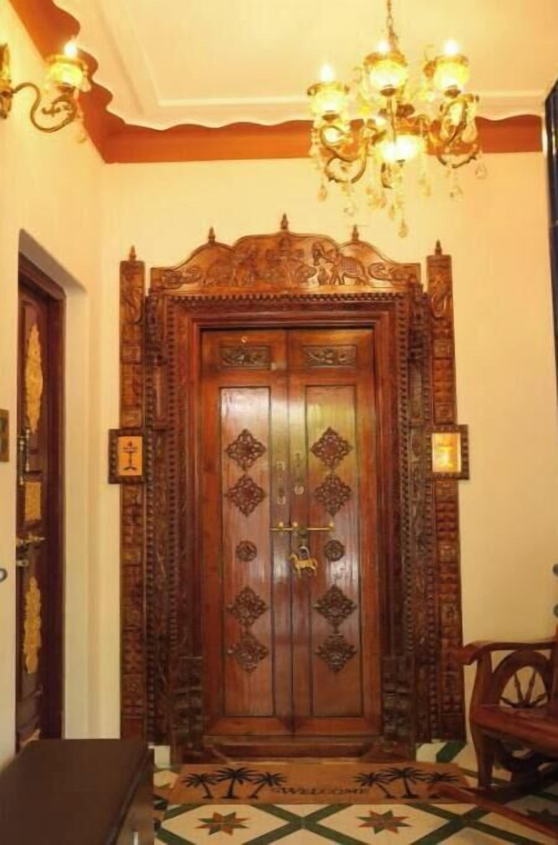 An ornate wooden door with intricate carvings and a chandelier above.