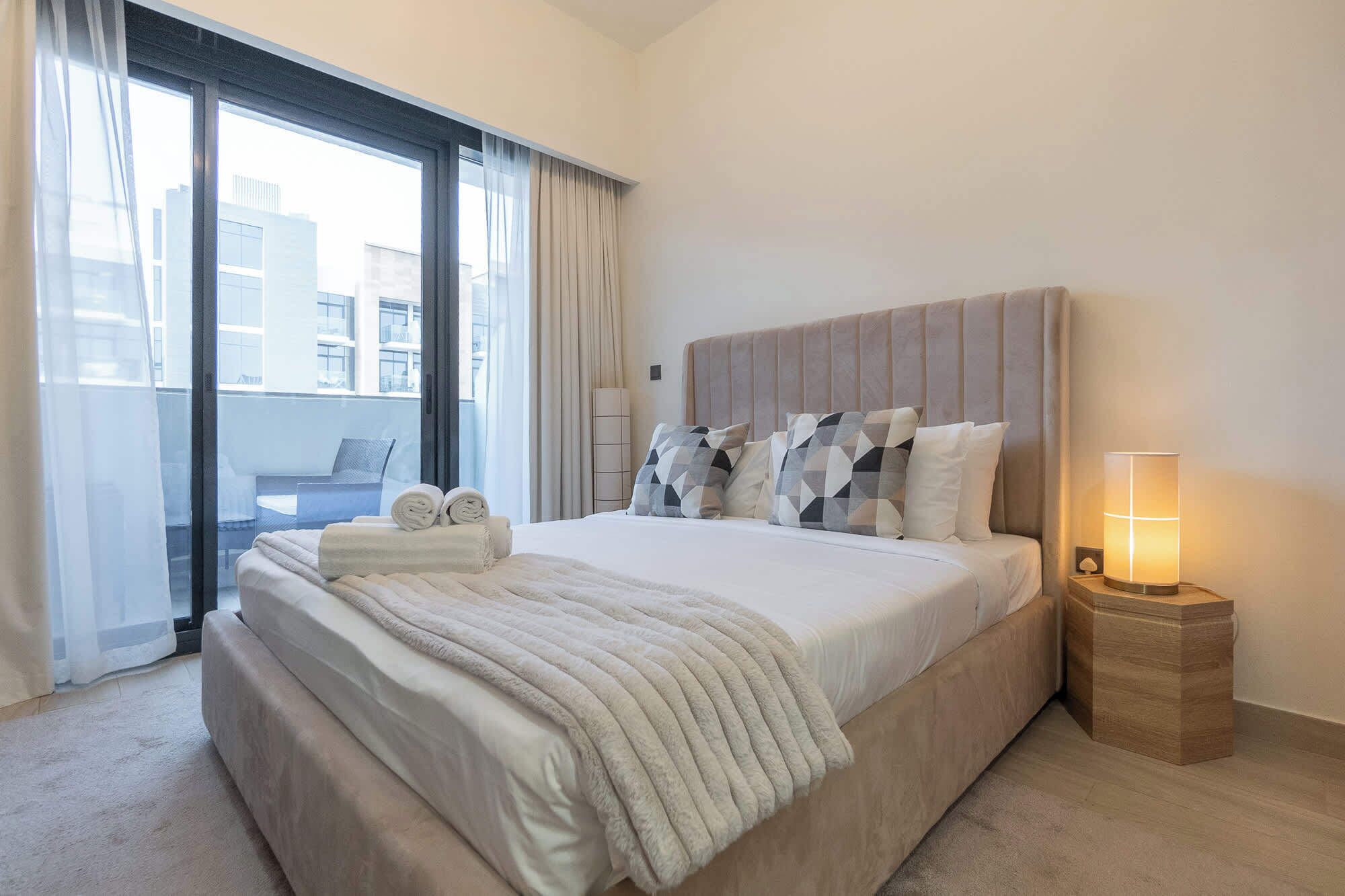 Ett hotellrum med en stor säng, en sänglampa och utsikt över staden genom fönstret.