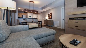 Una sala de estar moderna con un sofá modular, una pequeña mesa de comedor y un televisor montado en la pared.