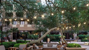 Un espacio al aire libre con mobiliario de madera e iluminación con guirnaldas.