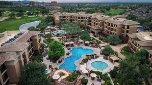Un resort con varias piscinas, campo de golf y exuberante jardinería.