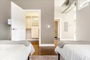 A bedroom with two beds, a walk-in closet, and a view of another room.