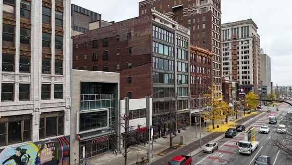 A street view with buildings, a bus lane, and cars.