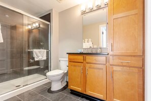 A modern bathroom with a glass-enclosed shower, a toilet, and wooden cabinets.