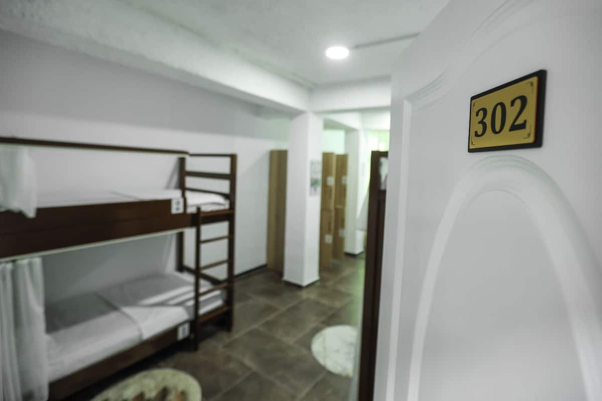 A room with bunk beds, a door with the number 302, and a hallway leading to another room.