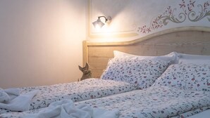 A neatly made bed with floral bedding, a wooden headboard, and a wall-mounted light fixture. - THE LADY OF THE LAKE (Molveno)