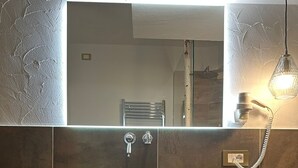 A modern bathroom with a large mirror, a dark basin, and a wooden vanity. - THE LADY OF THE LAKE (Molveno)