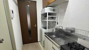 Une cuisine de taille réduite, équipée d’une cuisinière, d’un évier et de meubles blancs.