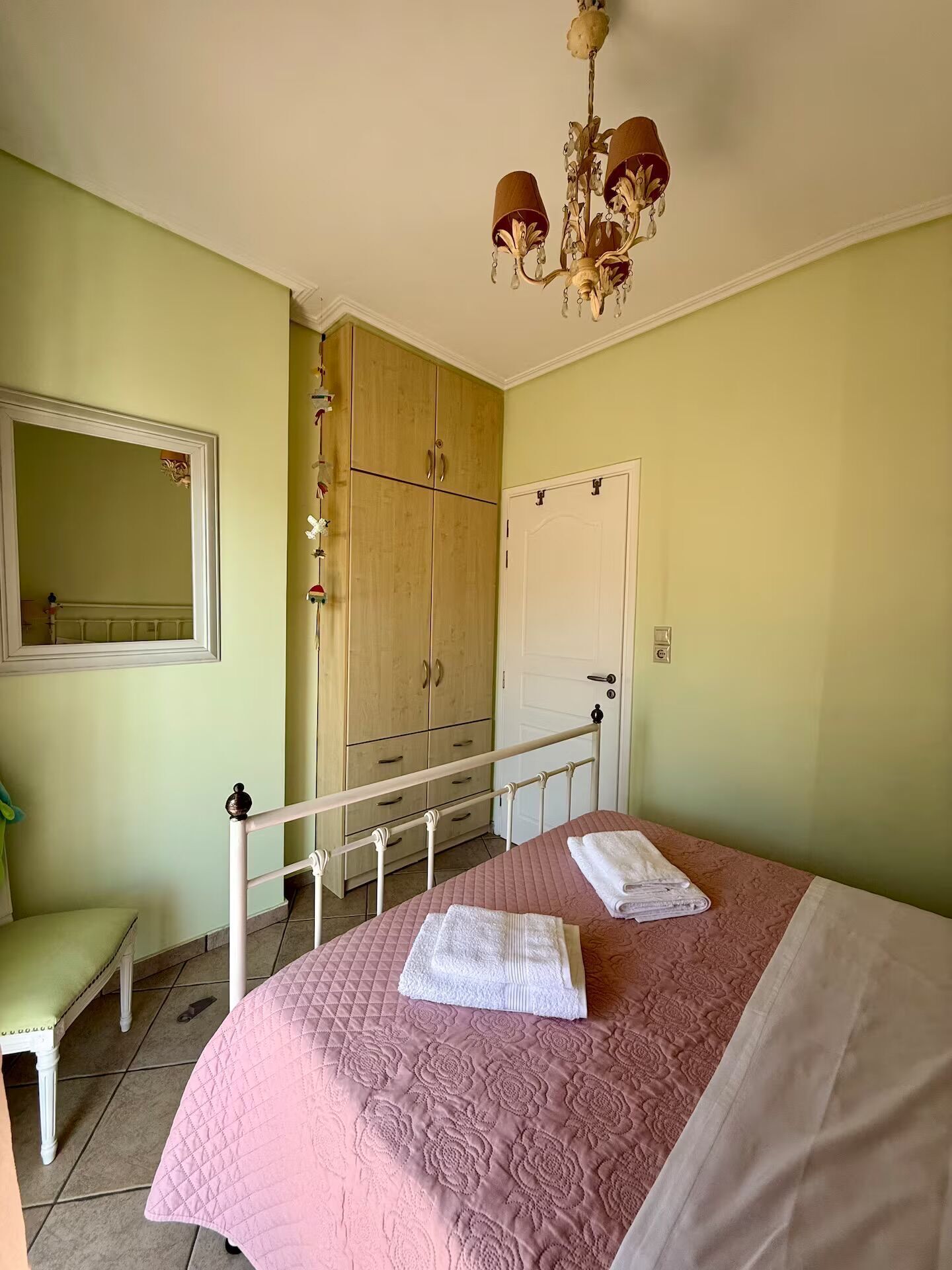 Een slaapkamer met een bed, een kledingkast, een spiegel en een kroonluchter.
