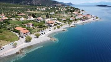 A coastal town with houses along the shoreline, clear blue water, and a hilly backdrop.