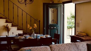 Una sala de estar con sofá, mesa de comedor, candelabro y una escalera.