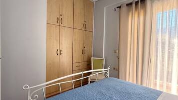A bedroom with a bed, a wardrobe, a chair, and a chandelier.