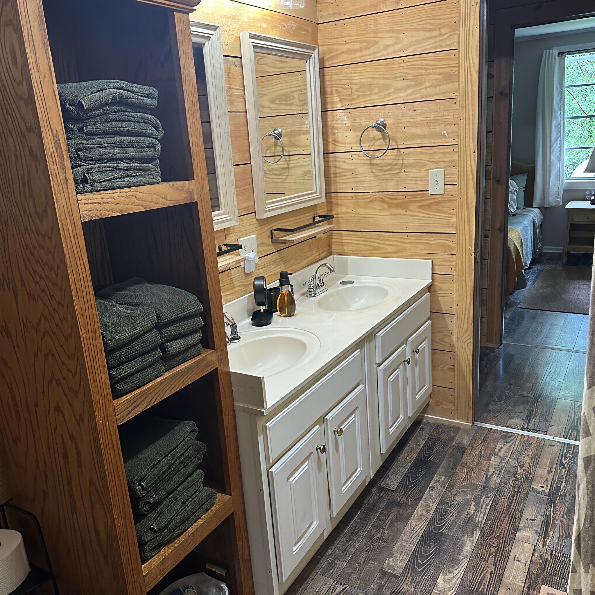 Un baño con paneles de madera, lavamanos doble y espejo sobre el lavamanos.