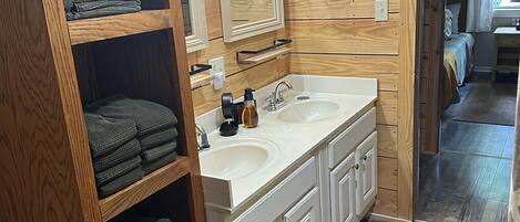 Un baño con paneles de madera, lavamanos doble y espejo sobre el lavamanos.