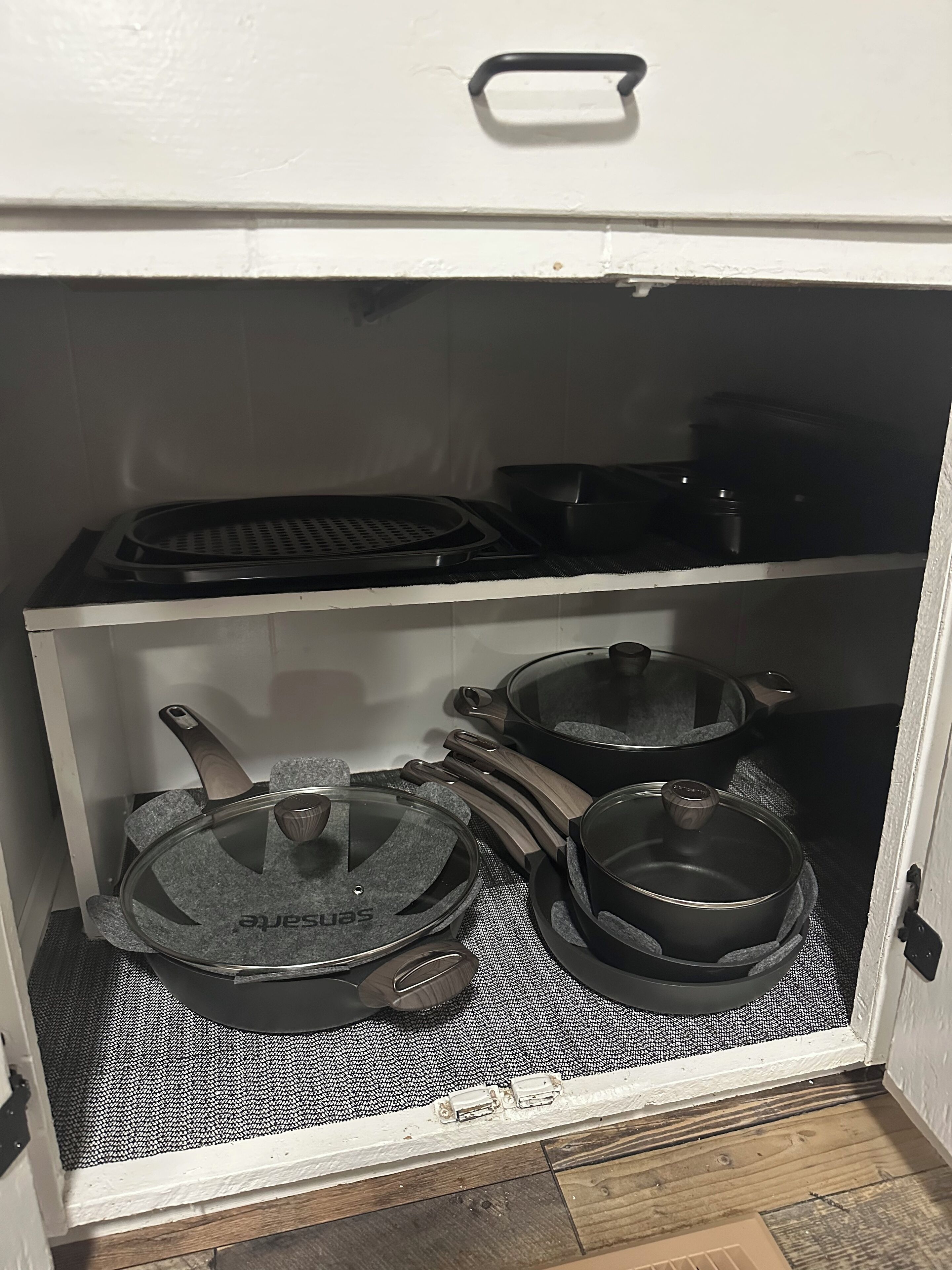 Cuina amb fogó, olles i paelles guardats en un armari.