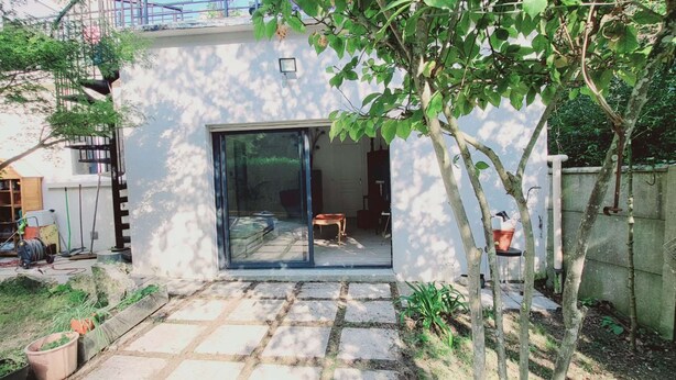 Ein modernes Haus mit Glastür, die zu einer Terrassenfläche führt.