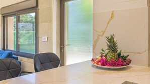 Een vergadertafel met een bloemstuk, een raam met uitzicht op groen, en een deur met een geëtste glazen panelen.