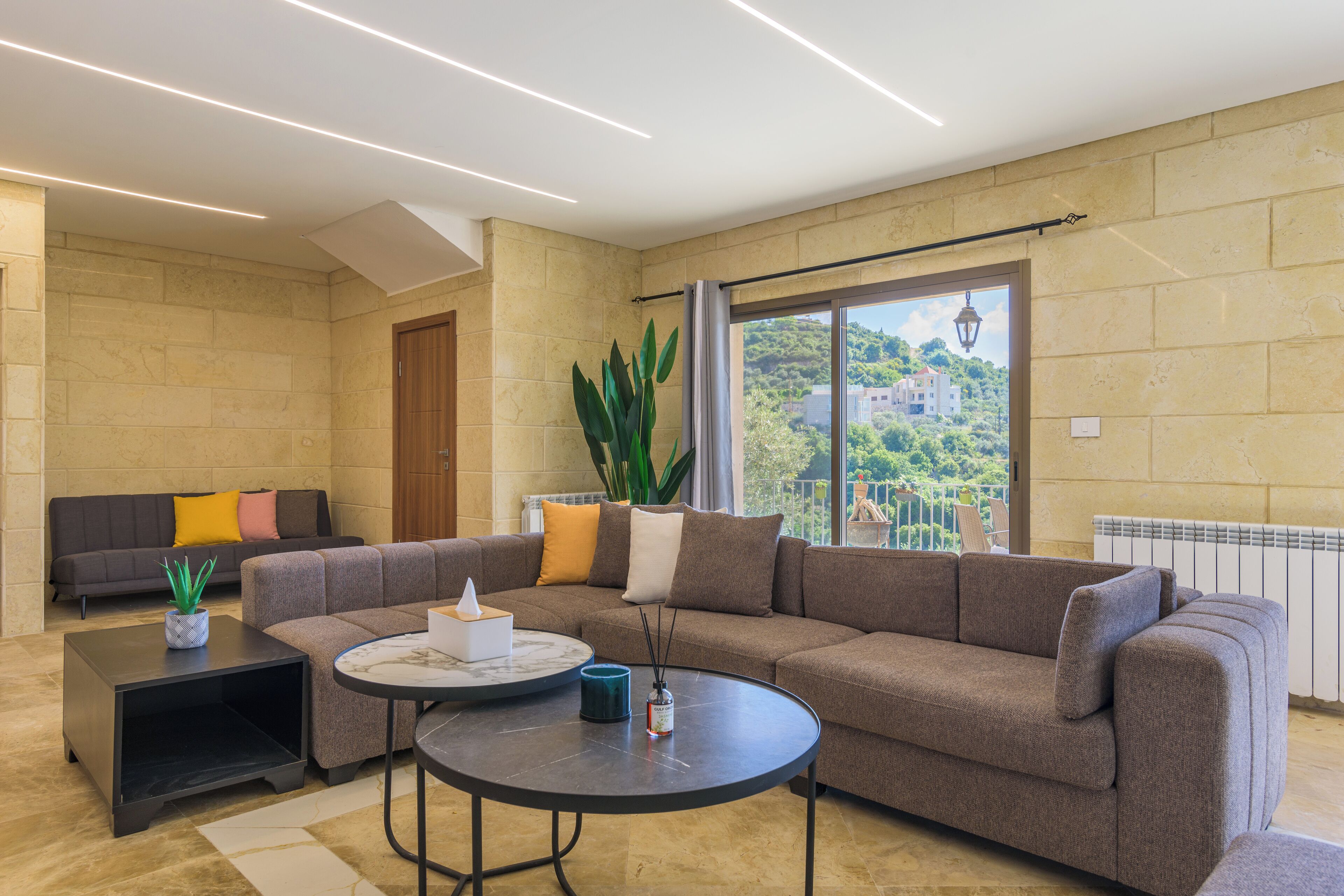 A modern living room with a sectional sofa, a round coffee table, and a potted plant.