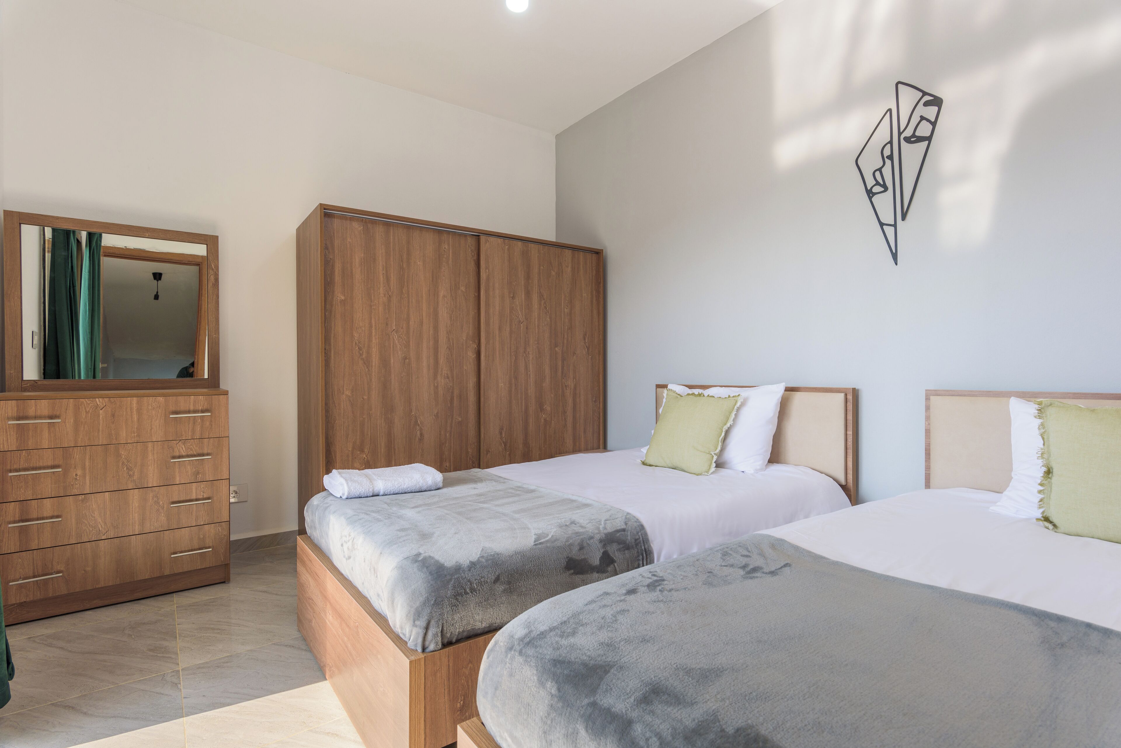 Un dormitorio con dos camas, un armario de madera y un espejo.