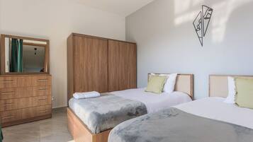 Un dormitorio con dos camas, un armario de madera y un espejo.
