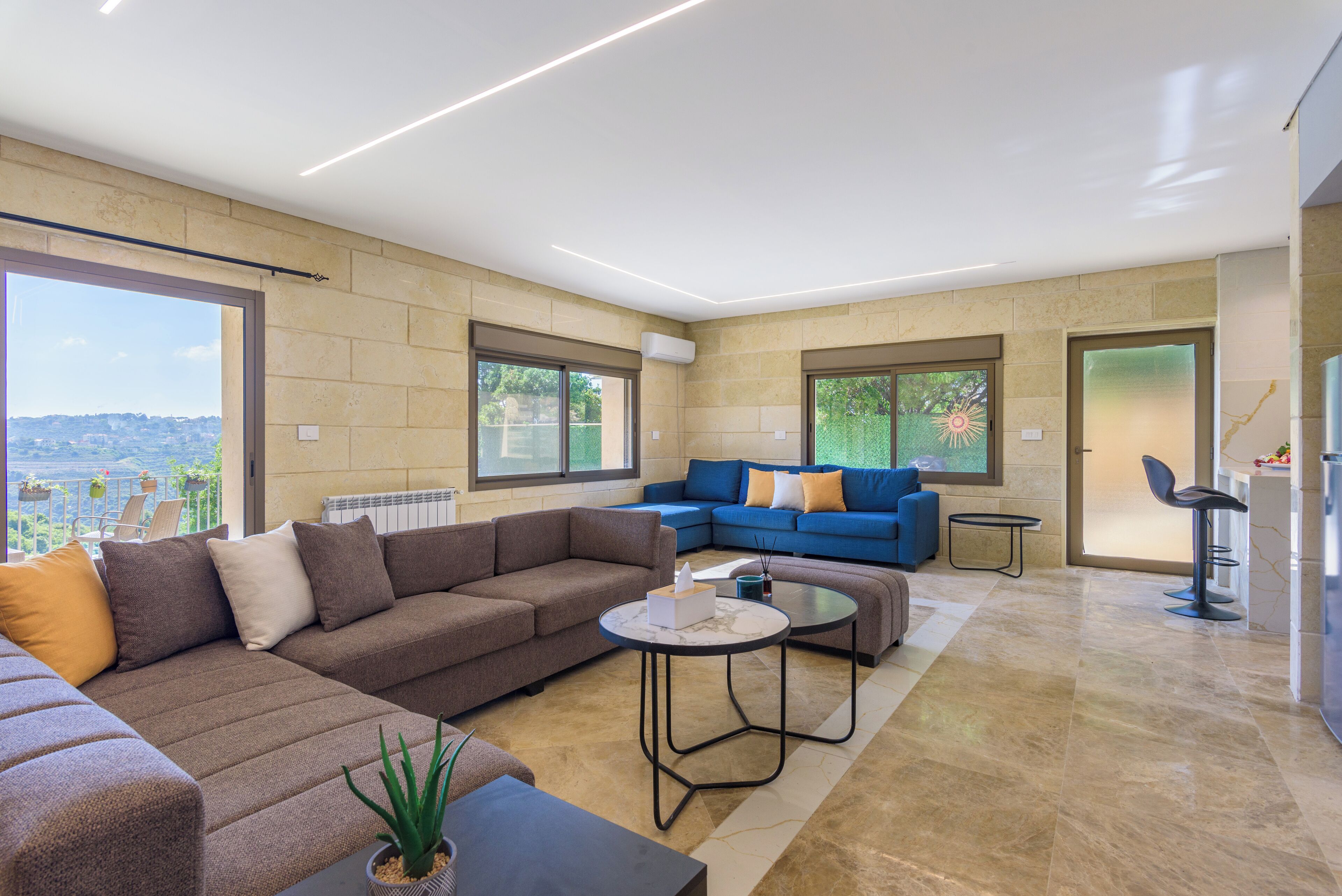 A modern living room with a sectional sofa, a coffee table, and a view of the city.