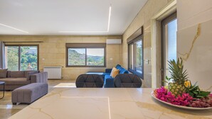 Een moderne woonkamer met een marmeren tafel, een bank en uitzicht op het omliggende landschap.