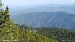 Eine gebirgige Landschaft mit einer kleinen Siedlung, eingebettet zwischen dichten Wäldern.