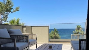 A balcony with a view of the ocean, featuring a sofa, a table, and a railing. - Akti Vigla Premium (Lesvos)