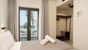A hotel room with a bed, a view of the sea, and a balcony with chairs. - Akti Vigla Premium (Lesvos)