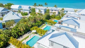 A coastal resort with multiple buildings, a swimming pool, and a view of the ocean. - Summer Breeze 7 Bedroom Home (Captiva)