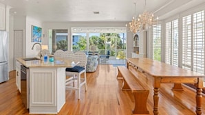 A spacious kitchen with a wooden island, a dining table, and a view of the outdoors. - Summer Breeze 7 Bedroom Home (Captiva)