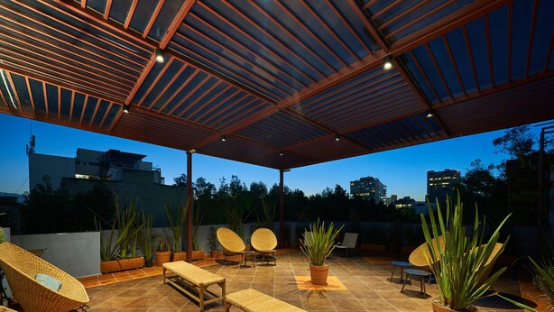 Une terrasse extérieure aménagée avec des meubles en osier, des plantes en pot et un sol carrelé.