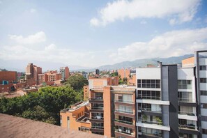 Paisagem urbana com edifícios modernos, incluindo uma construção de vários andares com sacadas e um edifício de cobertura plana com fachada retilínea.