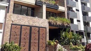 Un immeuble à plusieurs étages doté de balcons, d’une façade en briques et d’une entrée fermée par un portail.